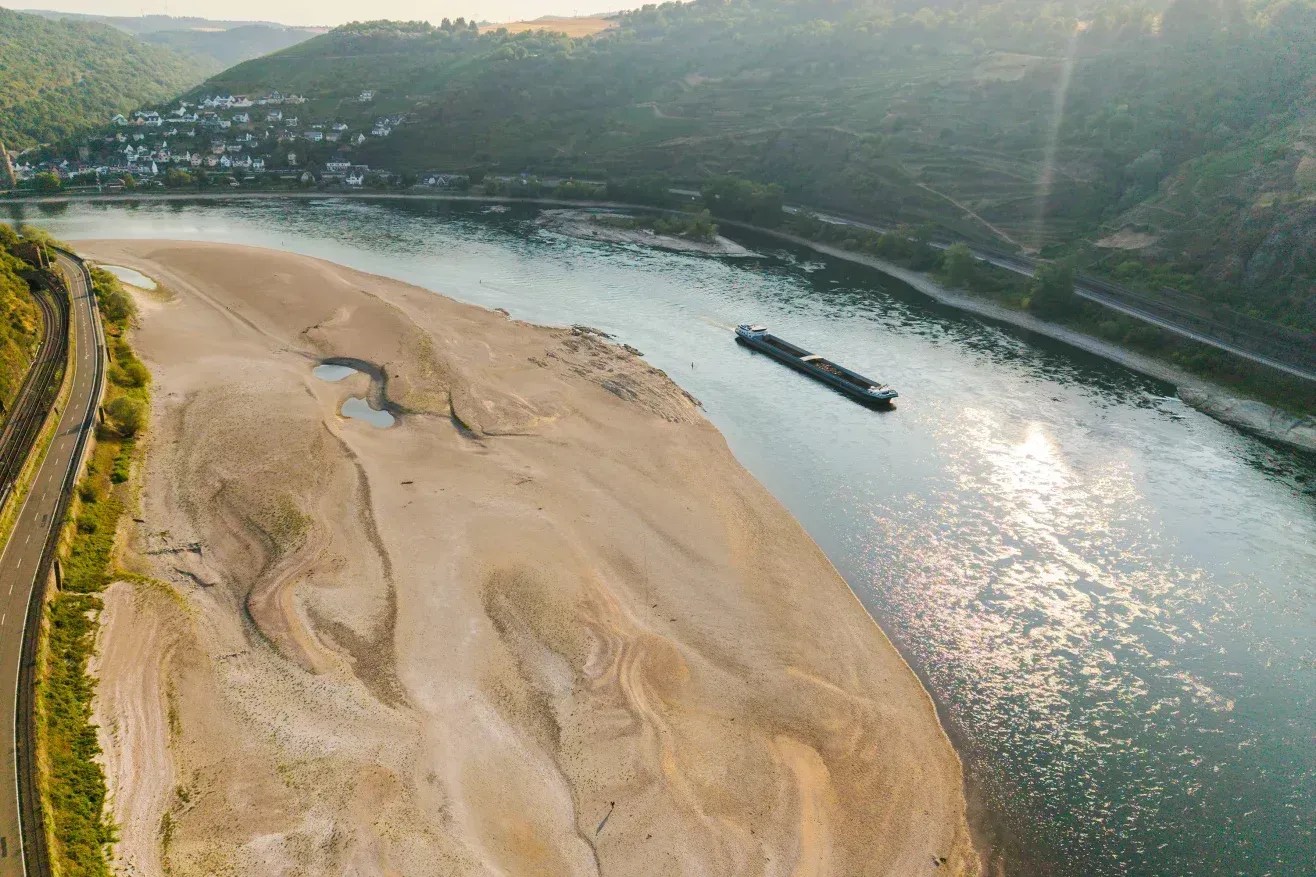 Um navio cargueiro passa por um enorme banco de areia exposto no rio Reno, perto de Oberwesel, na Alemanha, durante uma seca contínua e uma nova onda de calor, em 30 de julho de 2026 • Thomas Lohnes/Getty Images