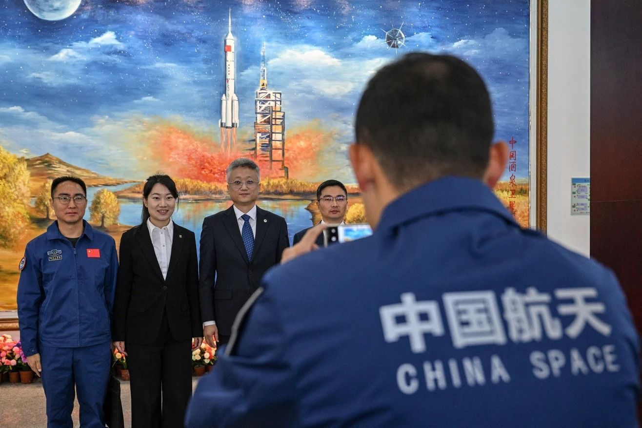 Zhang Jingbo (terceiro da esquerda para a direita), porta-voz do Programa Espacial Tripulado da China, posa com membros da equipe no Centro de Lançamento de Satélites de Jiuquan, na província de Gansu, China, em 2025 • Héctor Retamal/AFP/Getty Images