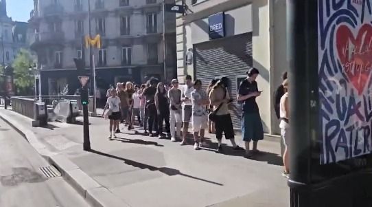 Clientes formam fila para comprar óculos de observação do eclipse solar em Paris, nesta quarta-feira • CNN