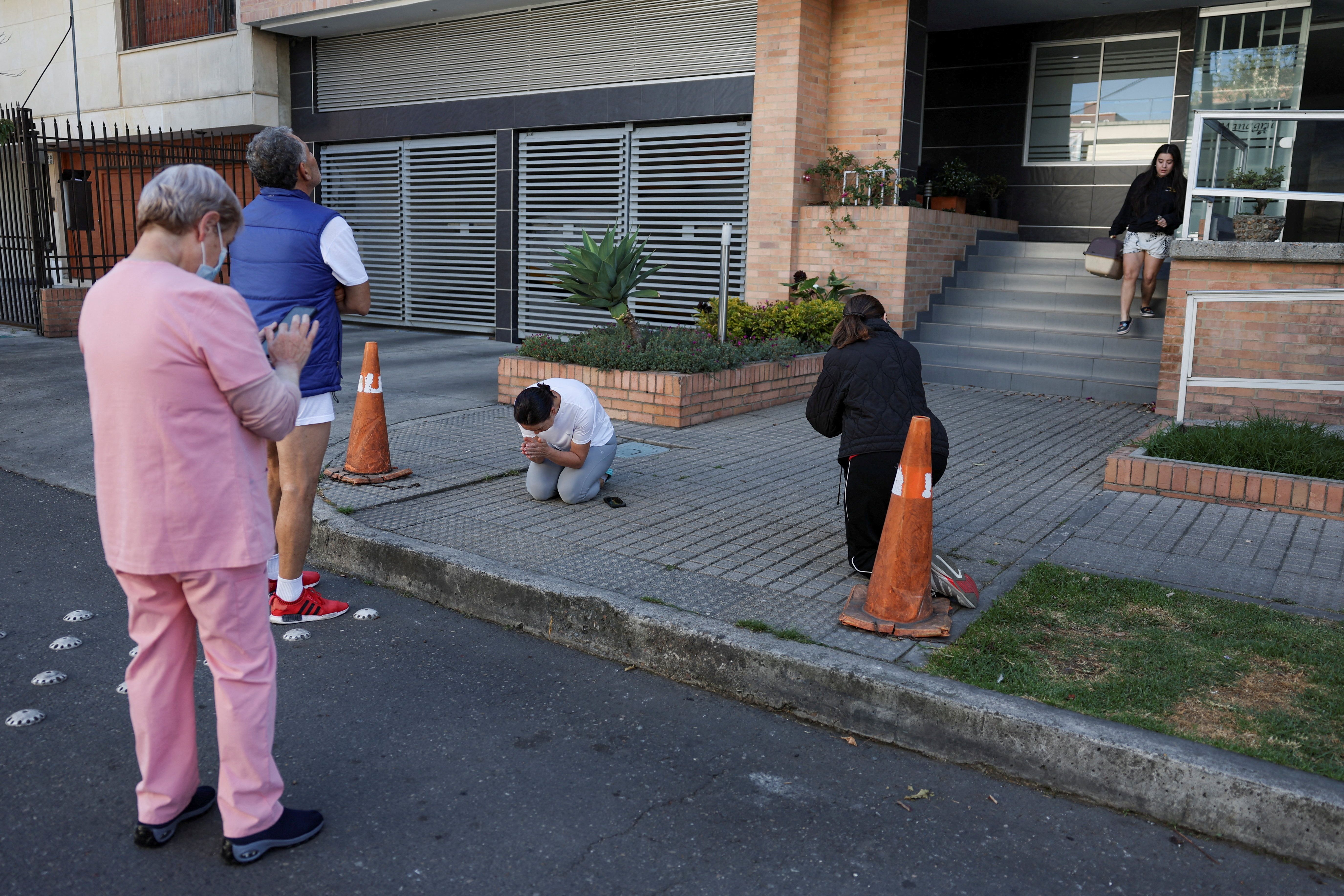 Uma mulher ora enquanto pessoas se reúnem do lado de fora de um prédio após um terremoto em Bogotá, na Colômbia • REUTERS