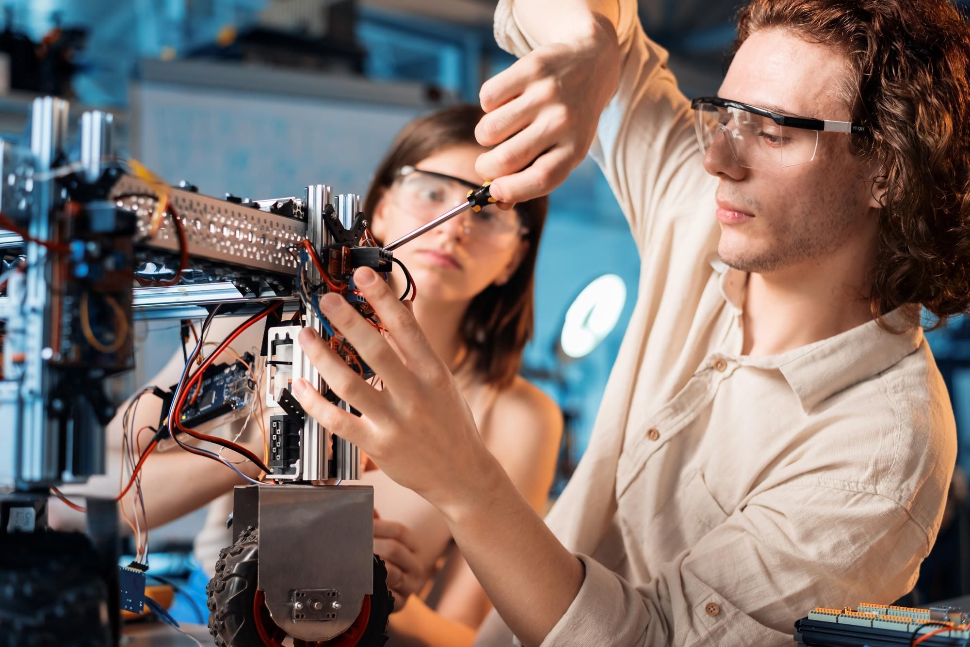 dois-jovens-com-óculos-de-p.roteção-montndo-robô-em-laboratório