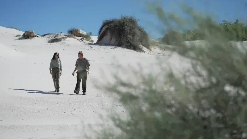 Bustos acompanha a jornalista da CNN, Erica Hill, em uma caminhada pelas dunas. • CNN/Jordan Guzzardo