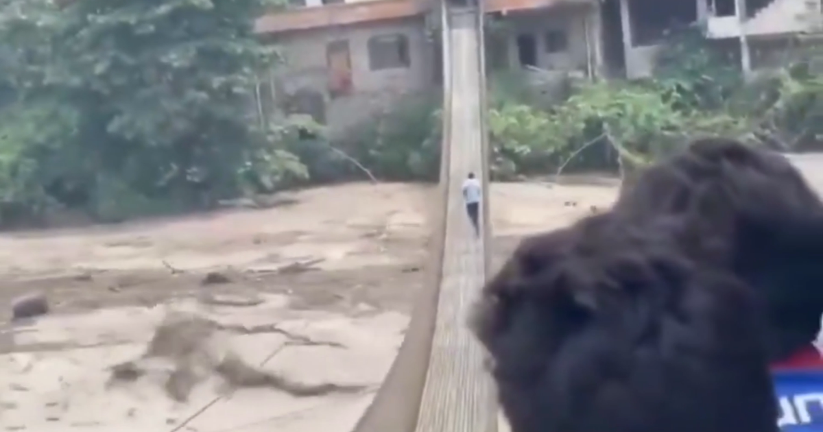 Homem atravessando ponte sob forte correnteza no Nepal