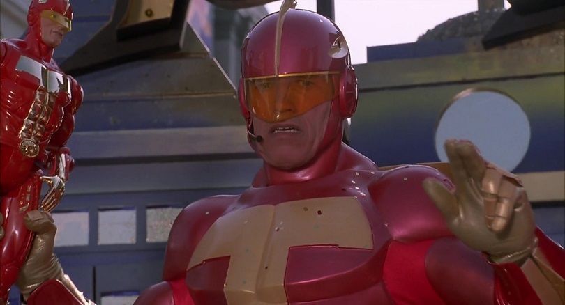Cena do filme 'Um Herói de Brinquedo' com Schwarzenegger vestindo Turbo Man.