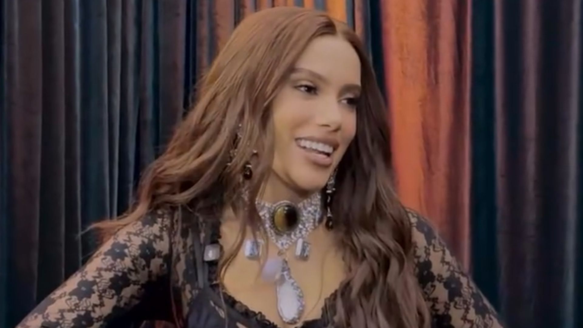 Cantora Anitta sorridente com blusinha de renda preta