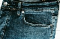Qual é a função do pino de metal nas laterais da calça jeans?