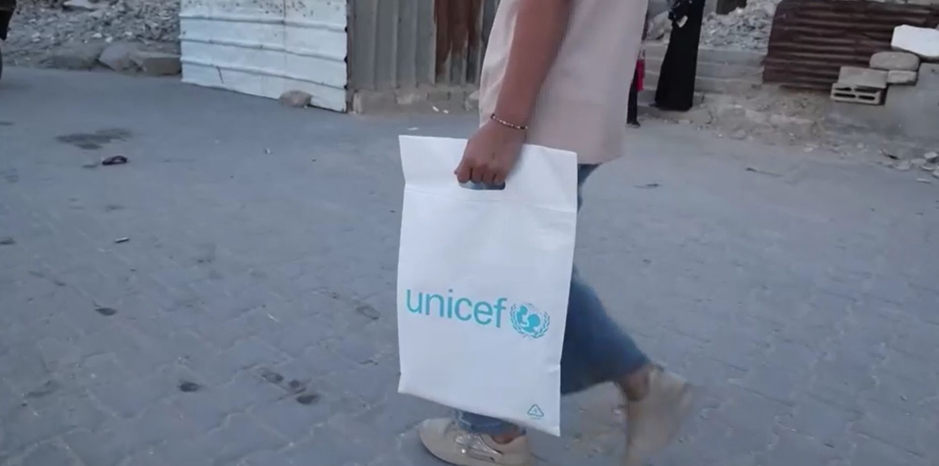 Criança segurando uma sacola da UNICEF em volta às aulas em Gaza em meio a guerra
