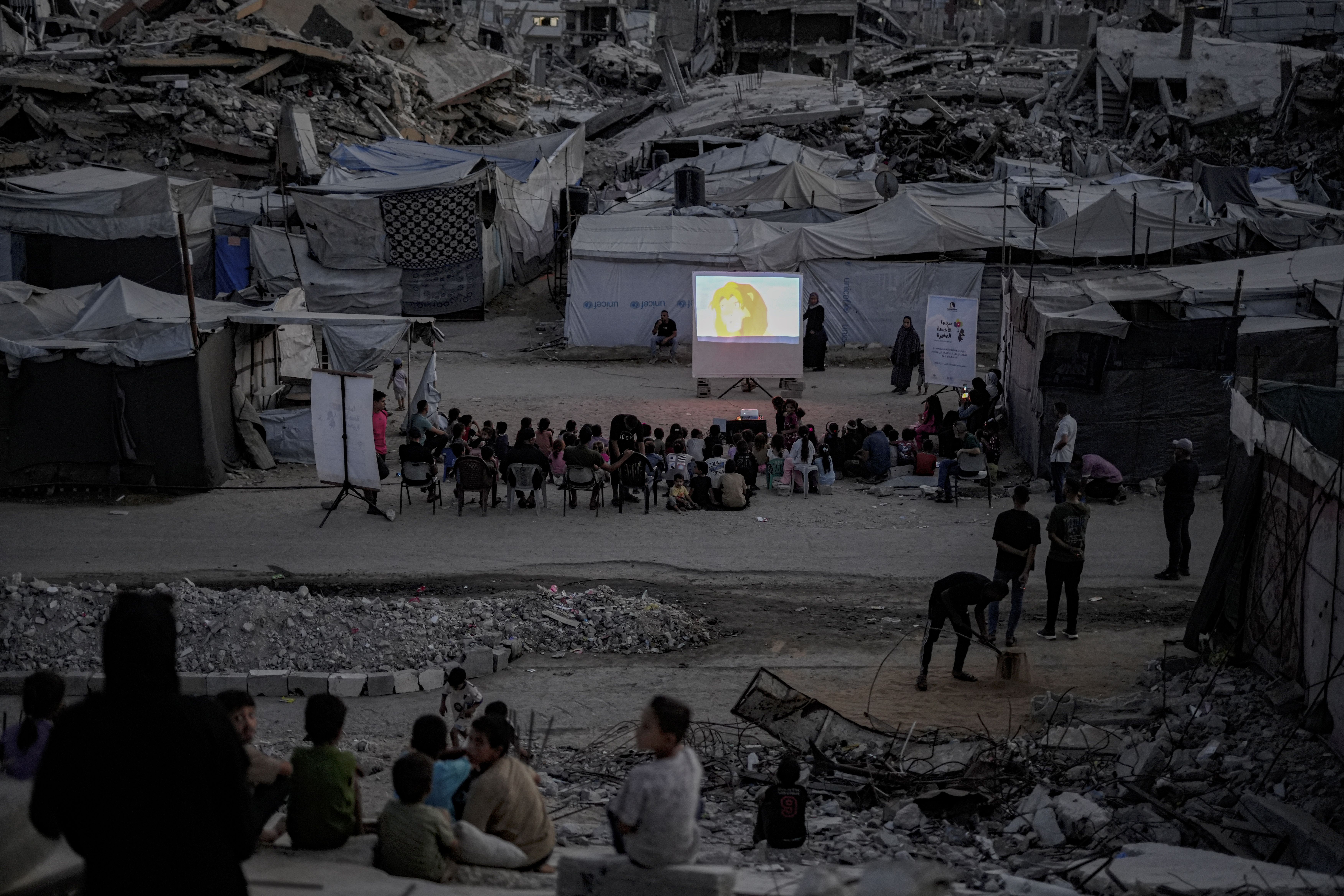 Palestinos, incluindo crianças, assistem a uma exibição de filme organizada pelo Little Wings Cinema no bairro de Sheikh Radwan, ao norte da Cidade de Gaza, em 30 de agosto de 2026. A iniciativa proporciona às crianças um espaço de lazer em
