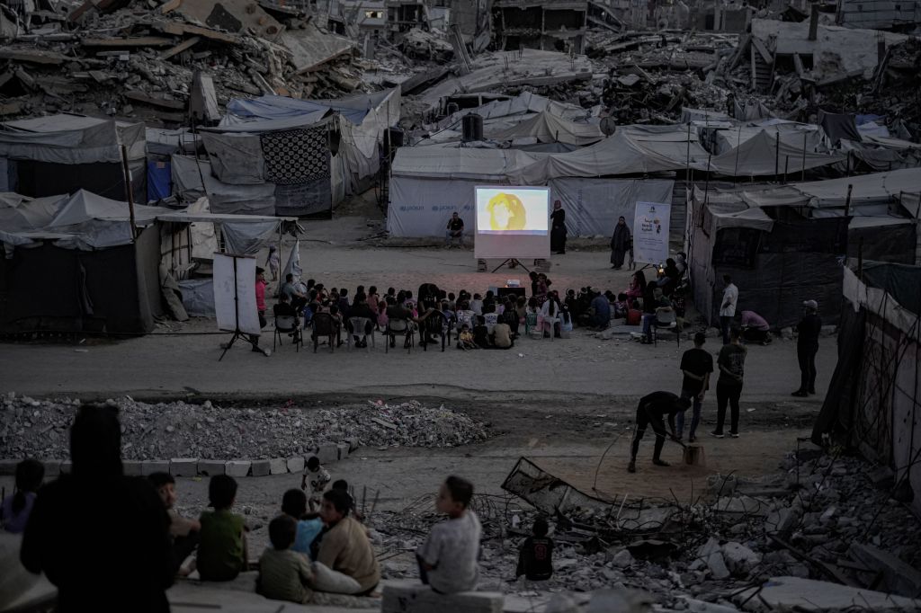 Palestinos, incluindo crianças, assistem a uma exibição de filme organizada pelo Little Wings Cinema no bairro de Sheikh Radwan, ao norte da Cidade de Gaza, em 30 de agosto de 2026. A iniciativa proporciona às crianças um espaço de lazer em meio às condições difíceis e à destruição generalizada causadas pela guerra entre Israel e o Hamas.