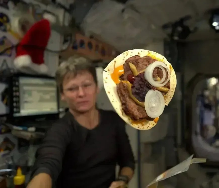 Comandante da Expedição 51, Peggy A. Whitson, exibindo o hambúrguer que preparou usando uma tortilla. • NASA