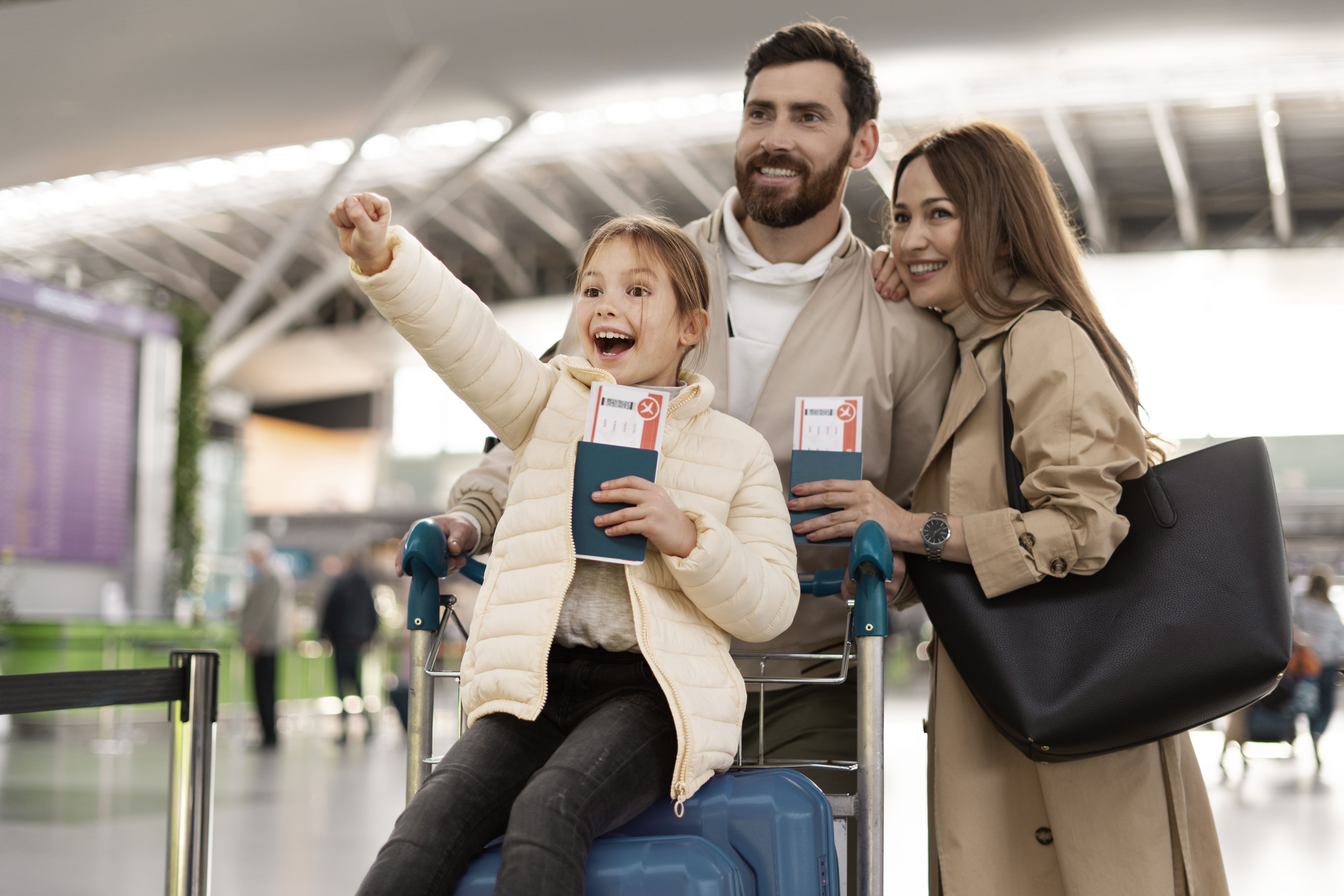 Família com pais e uma criança sorri com os passaportes nas mãos em viagem internacional.