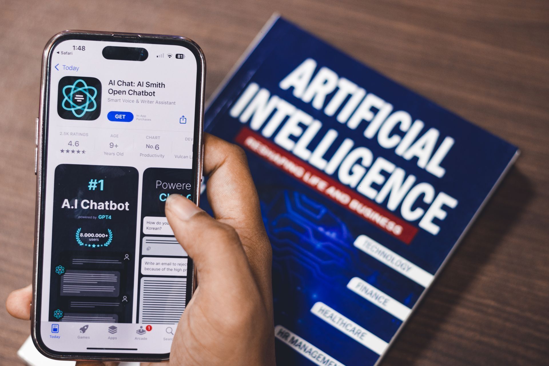 Pessoa utiliza aplicativo de inteligência artificial em smartphone ao lado de livro sobre IA