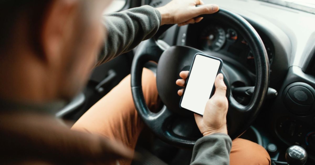 Motorista com celular ao volante na cidade.