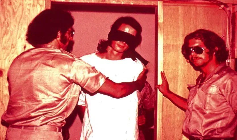 Cena de uma prisão simulada com participantes impersonando guardas e prisioneiros