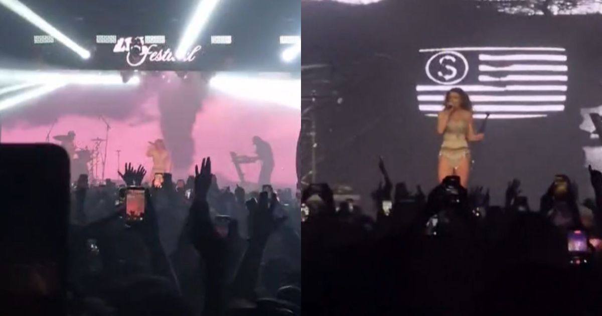 Pessoas no festival tentando se refrescar com leques enquanto o ambiente fechado permanece abafado