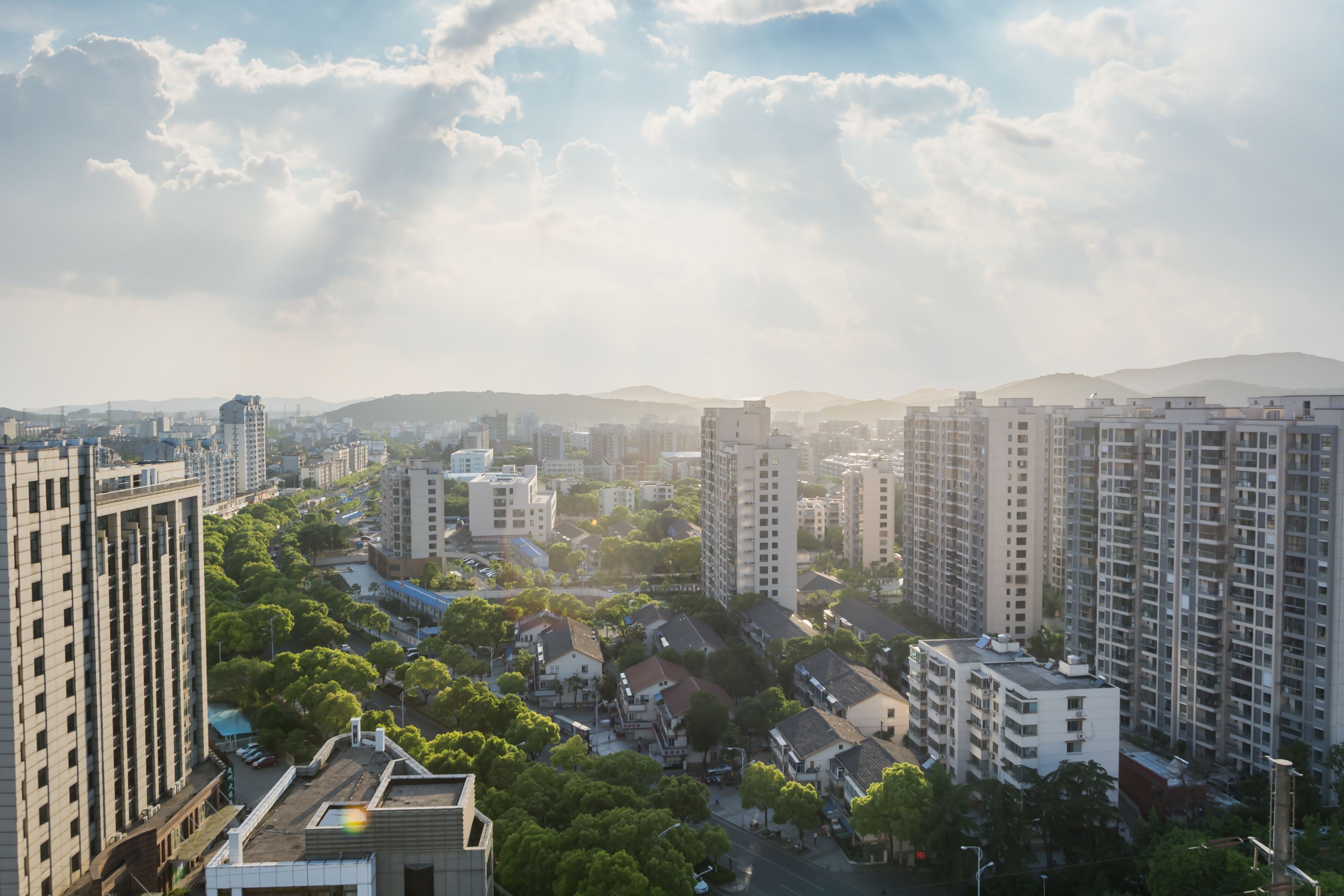 Vista de cima de um bairro residencial, com prédios nas extremidades e casas no centro com árvores dispostas no centro da foto