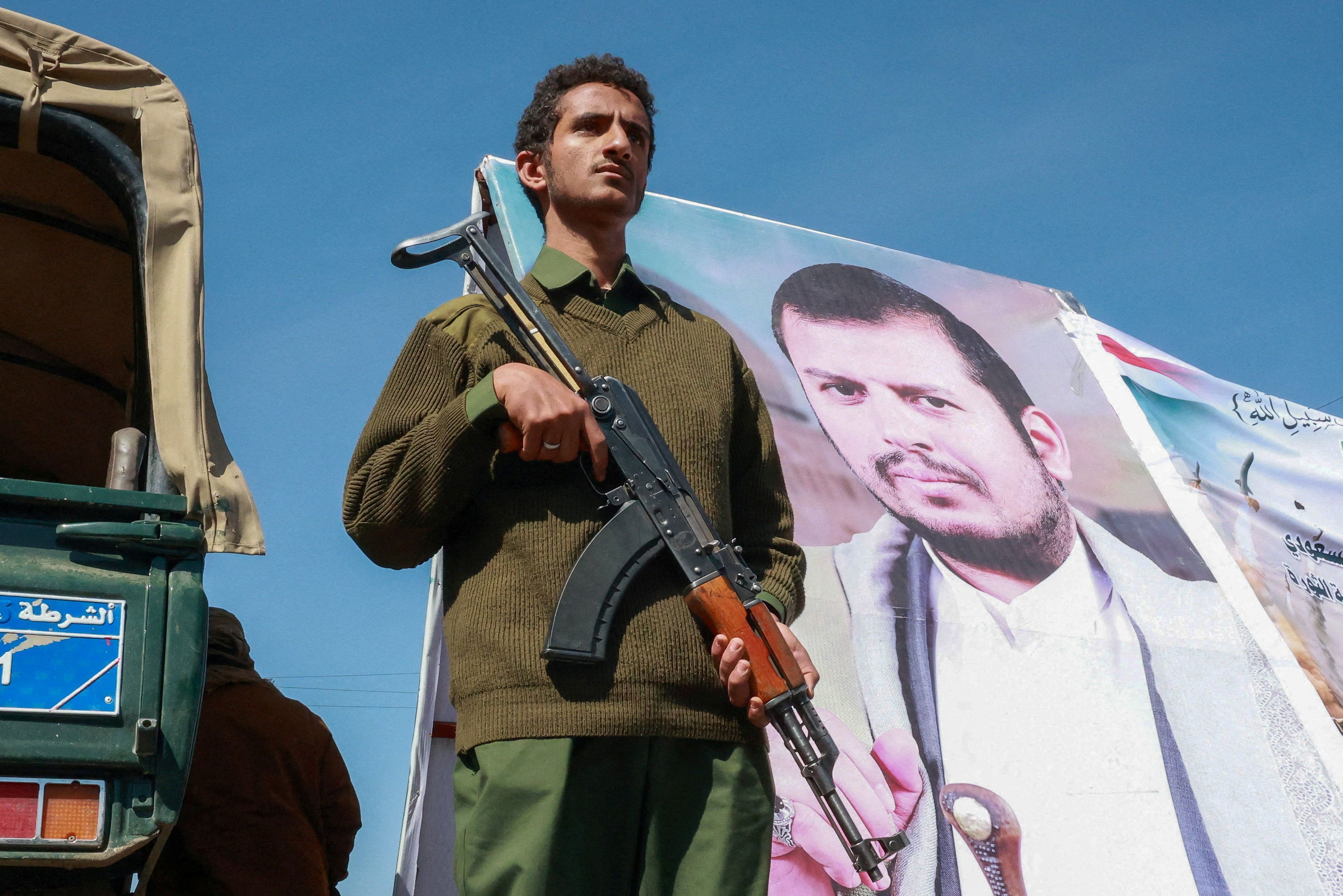 Membro das forças de segurança houthis ao lado de cartaz do líder houthi Abdul-Malik al-Houthi em Sanaa 7 de outubro de 2026 REUTERS/Mohammed al-Mahdi • REUTERS