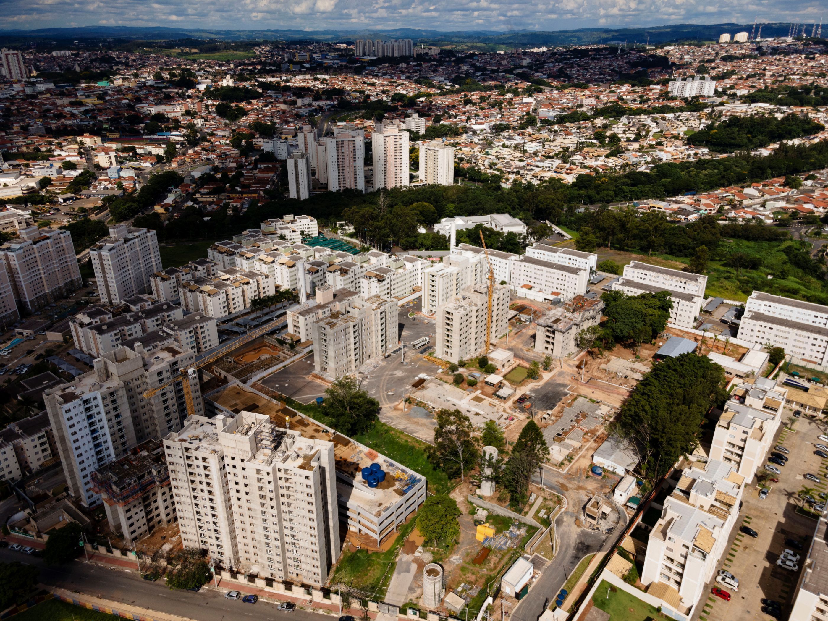 Vista aérea de uma cidade com muitos edifícios, destacando a densidade urbana e a diversidade arquitetônica, com destaque para prédios em construção