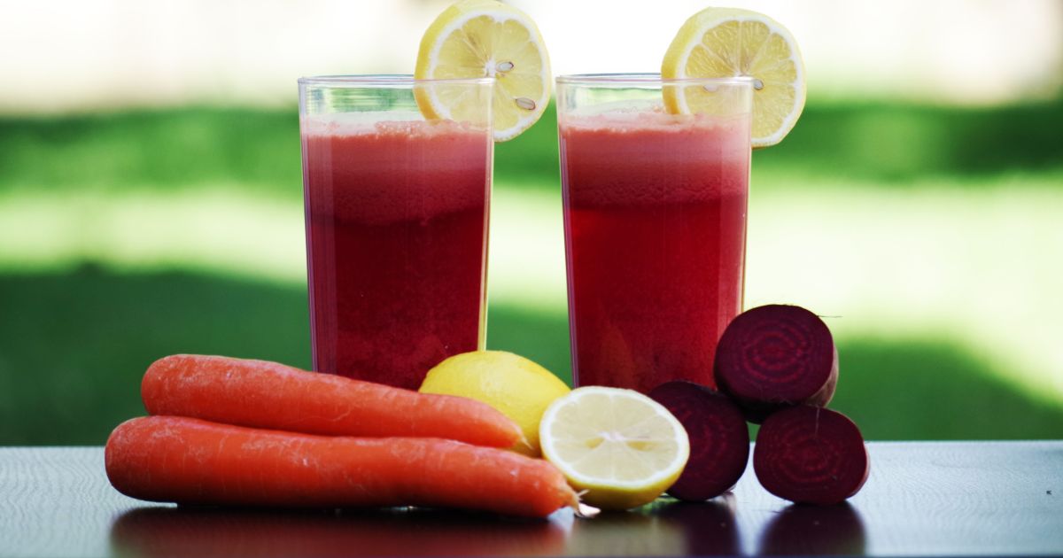 Copo de suco de beterraba e limão com ingredientes ao redor