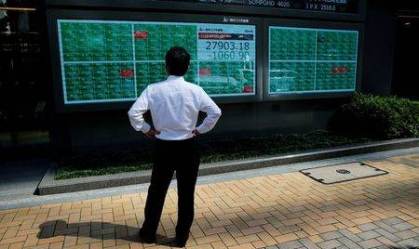 Homem observa painel eletrônico com cotações do mercado financeiro.
