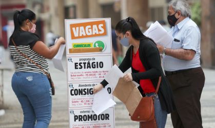Pessoas buscam emprego em listagem de vagas no centro de