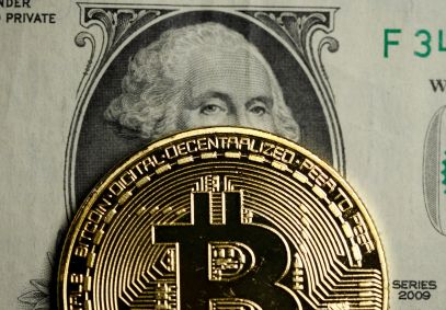 Representação do Bitcoin em cima de uma nota de dólar
