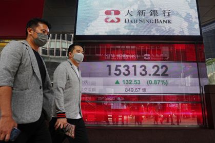 Pessoas passam em frente a painel que mostra o índice acionário Hang Seng, de Hong Kong, no distrito central de Hong Kong