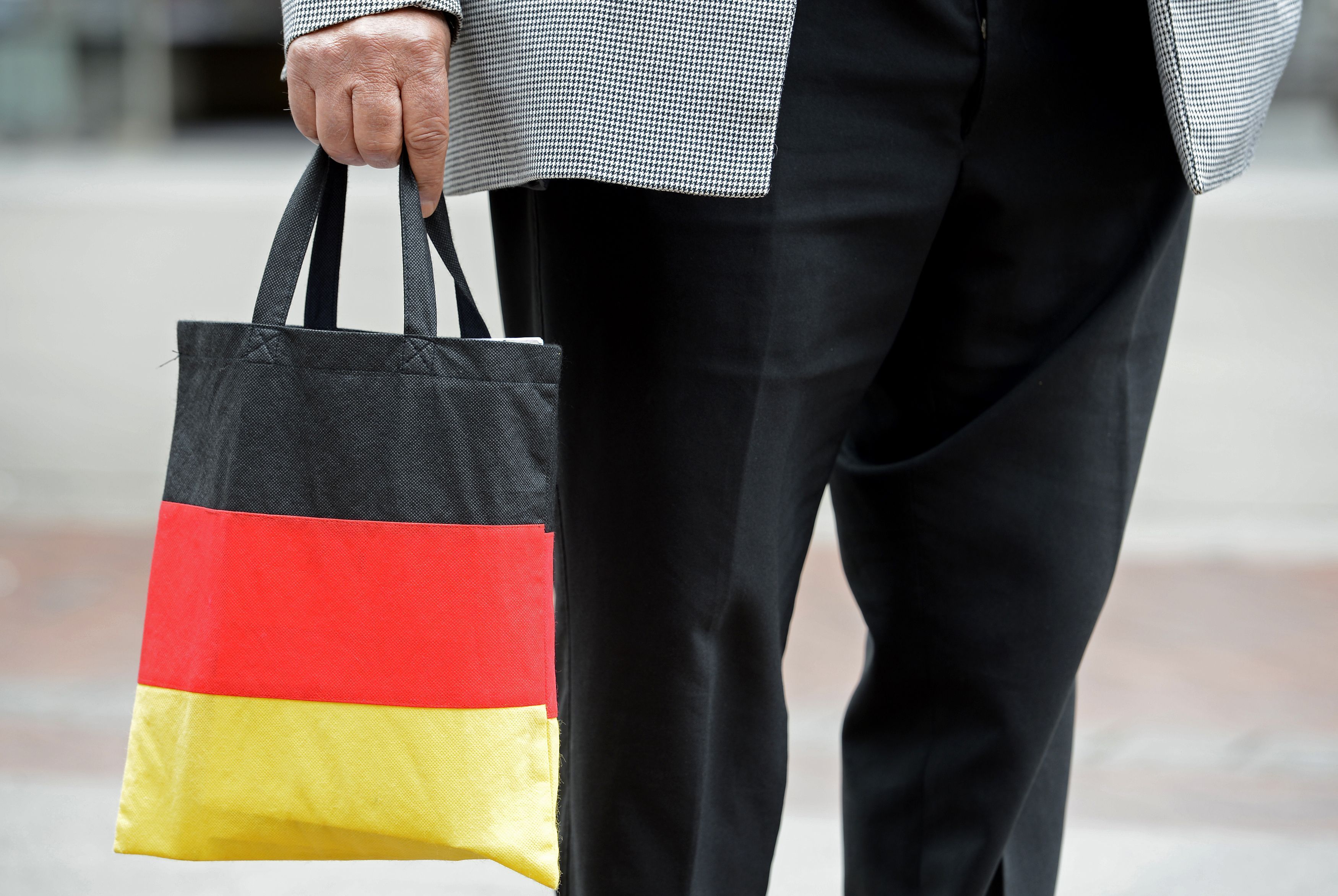 Homem carrega sacola de compras nas cores da bandeira da