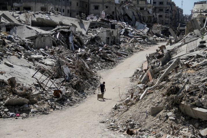 Um palestino caminha entre escombros de edifícios, destruídos durante a ofensiva militar de Israel em Beit Lahia, no norte da Faixa de Gaza • 12/06/2024 REUTERS/Mahmoud Issa