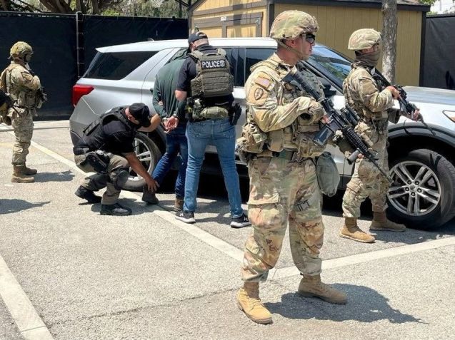 Policiais detêm uma pessoa em um local identificado como Los Angeles • Policiais detêm uma pessoa ao lado de membros da Guarda Nacional em um local identificado como Los Angeles, nesta imagem divulgada em 10 de junho de 2025 @ICEgov via X/via REUTERS
