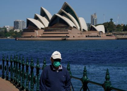 Homem com máscara caminha em frente à Casa da Ópera de Sydney; Austrália registra crescimento dos casos de Covid-19