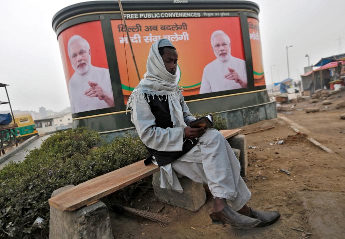 Muçulmano lê Alcorão em frente a um outdoor com o primeiro-ministro da Índia, Narendra Modi, em Nova Délhi / 20/1/2015 REUTERS/Adnan Abidi