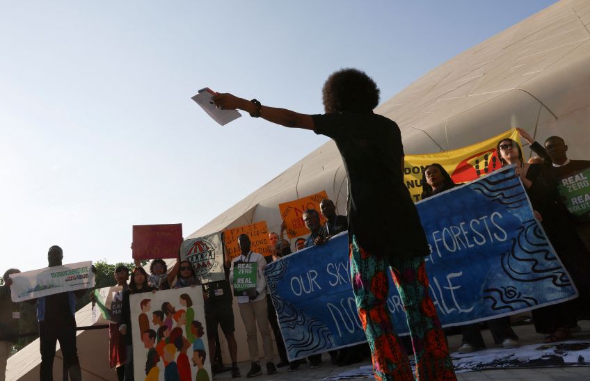Ativistas seguram cartazes durante protesto na COP28 em Dubai / 08/12/2023 REUTERS/Thaier Al-Sudani