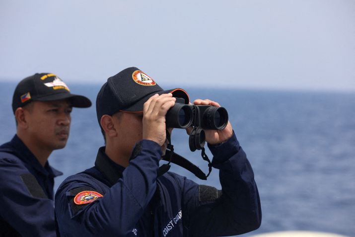 Membro da guarda costeira das Filipinas observa por binóculo durante missão de reabastecimento de tropas estacionadas em navio ancorado no Mar do Sul da China / 04/10/2023 REUTERS/Adrian Portugal