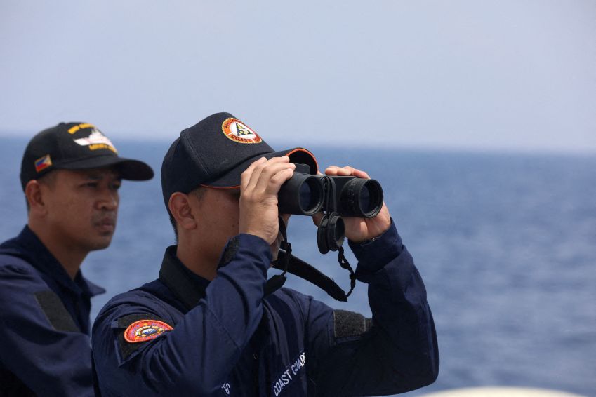 Membro da guarda costeira das Filipinas observa por binóculo durante missão de reabastecimento de tropas estacionadas em navio ancorado no Mar do Sul da China / 04/10/2023 REUTERS/Adrian Portugal