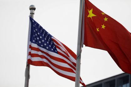 Bandeiras dos EUA e da China do lado de fora de prédio de empresa norte-americana em Pequim