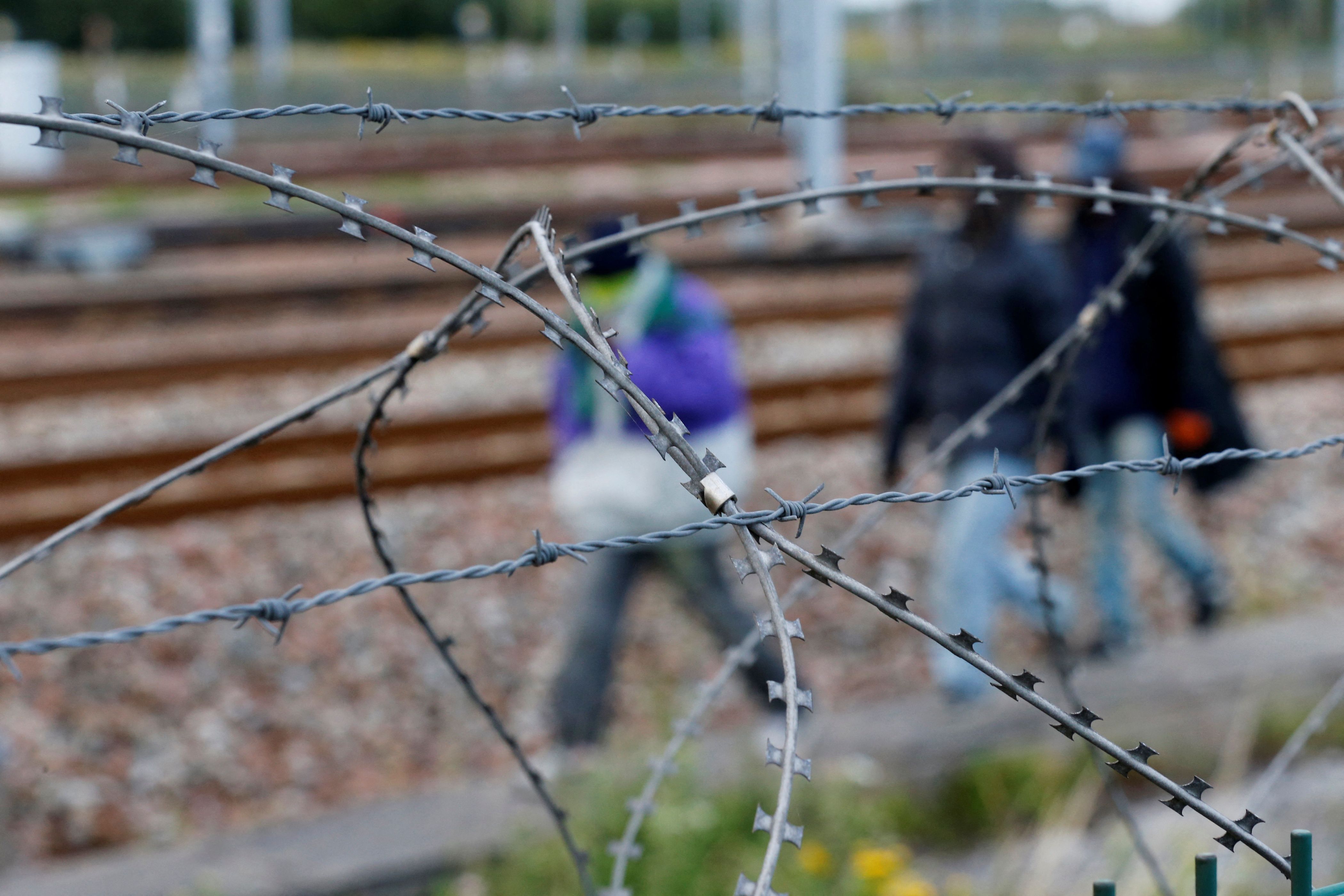 Arame farpado envolve imigrantes perto dos trilhos do trem que