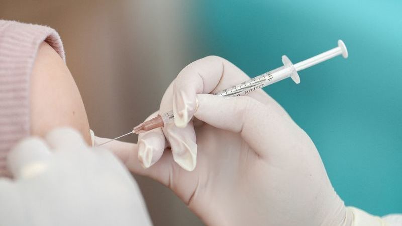 Uma enfermeira aplicando a vacina - com um aplicador com agulha - vacina essa da Covid no braço de uma pessoa branca