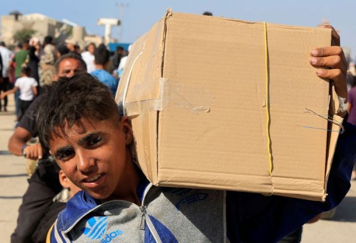 Palestino carrega caixa enquanto outros se reúnem perto de local de distribuição de ajuda administrado pela Fundação Humanitária de Gaza, apoiada pelos EUA, em Rafah, no sul da Faixa de Gaza • 27/05/2025 REUTERS/Hatem Khaled