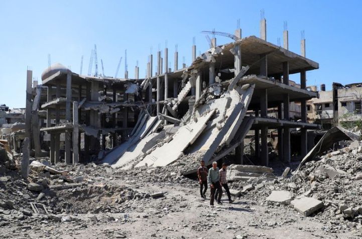 Palestinos passam por prédio destruído enquanto inspecionam danos causados pela operação israelense no bairro de Sabra, na Cidade de Gaza • 08/10/2025 REUTERS/Ebrahim Hajjaj