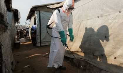Profissional de saúde desinfeta área no leste da República Democrática